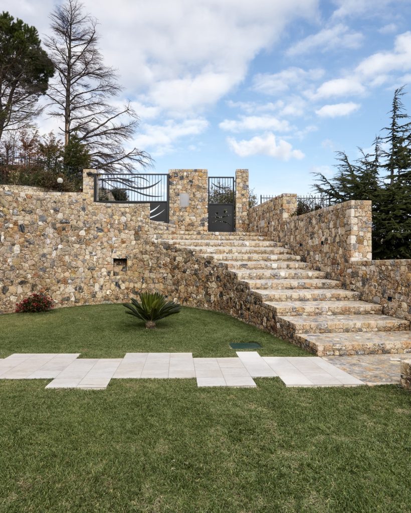 exteriors shots of a modern villa in foreground the masonry staircase that leads to iron gate